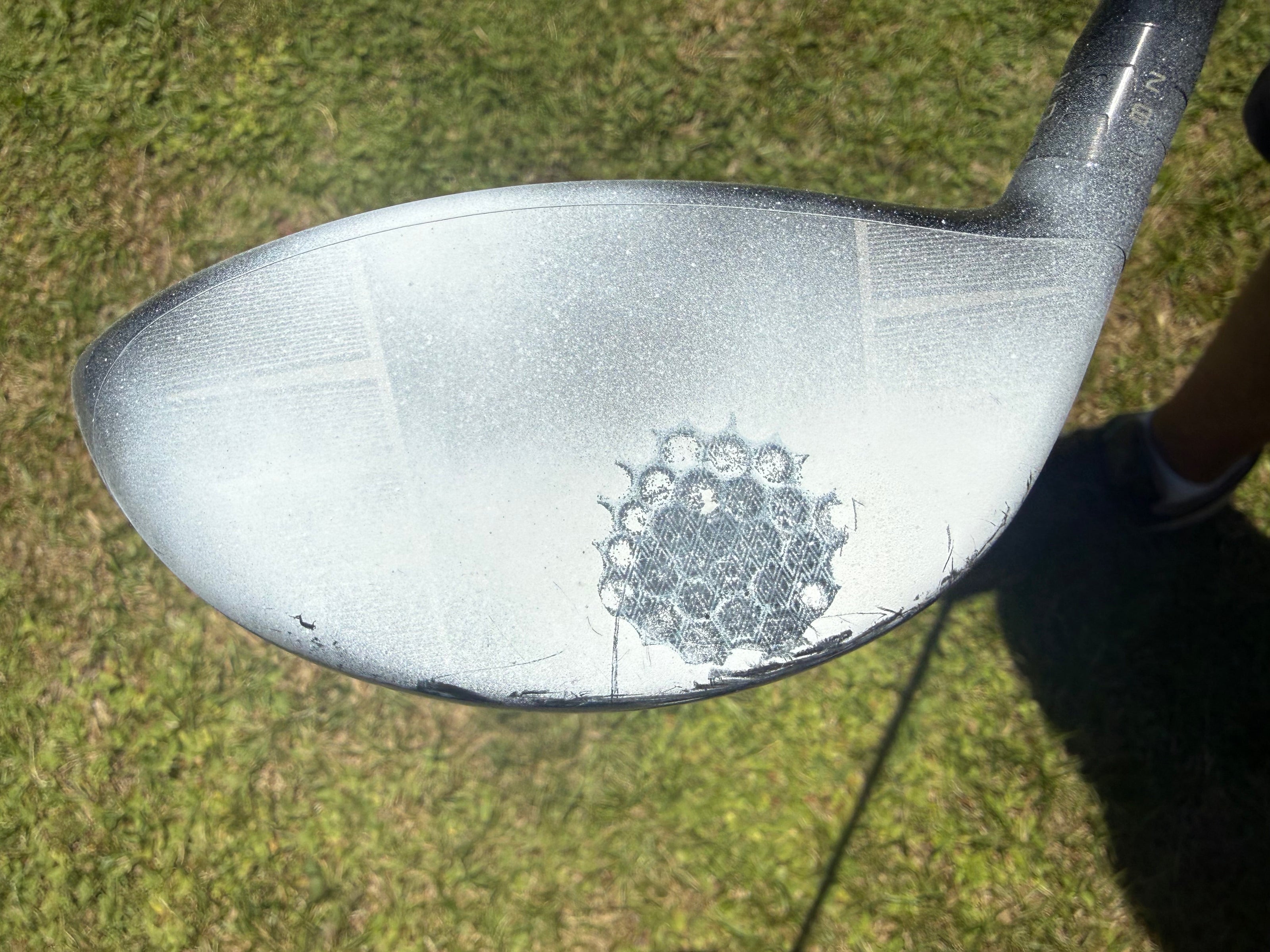 Golf club head with a visible brand logo on a grass background