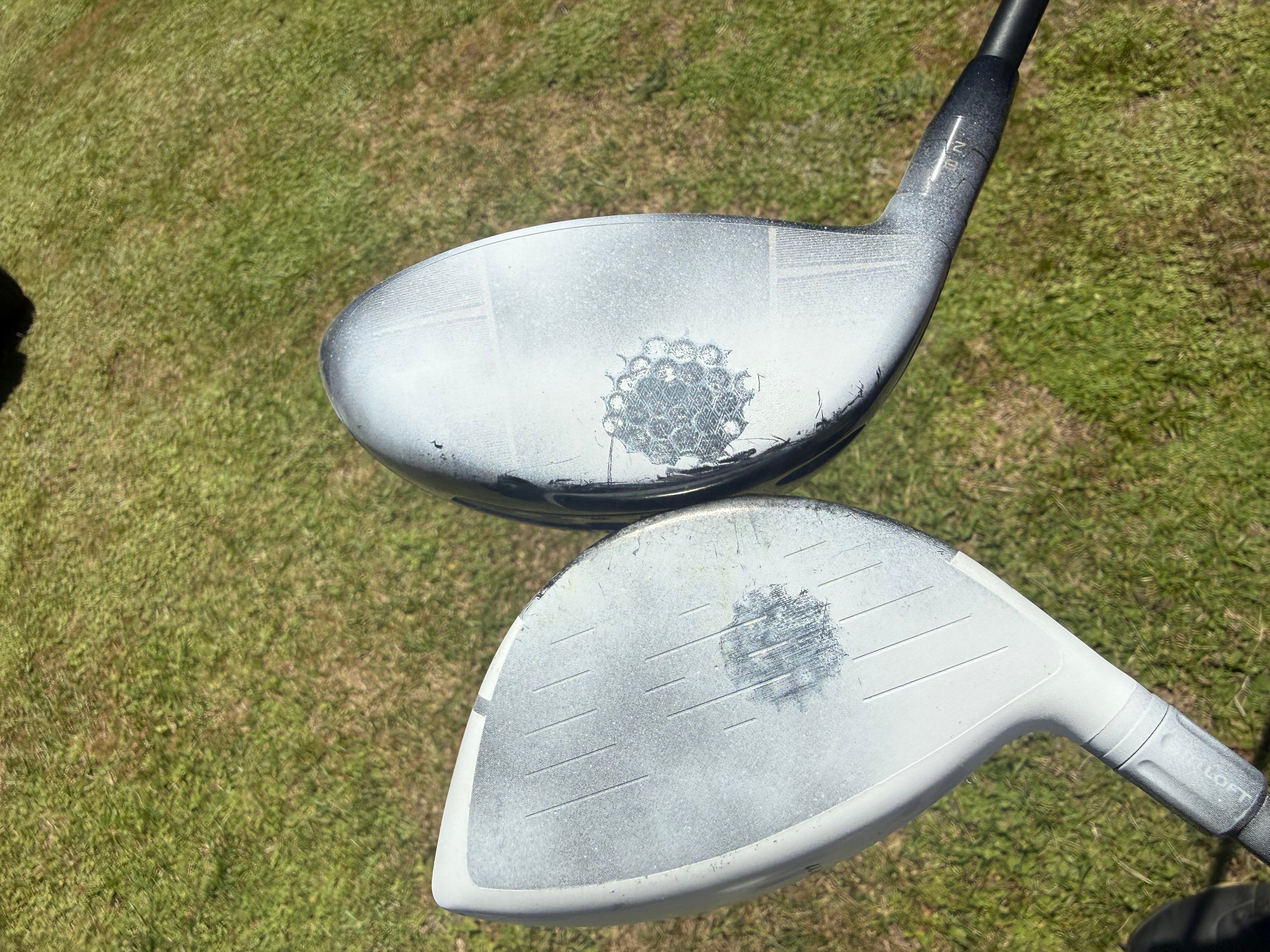 Two golf club heads on a grassy surface